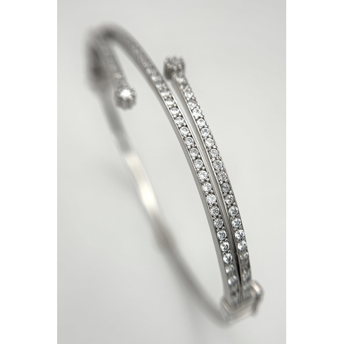 554 - A 14K White Gold and Diamond Crossover Bangle Bracelet. c.100 micro-claw pave set diamonds of c.1ctw... 