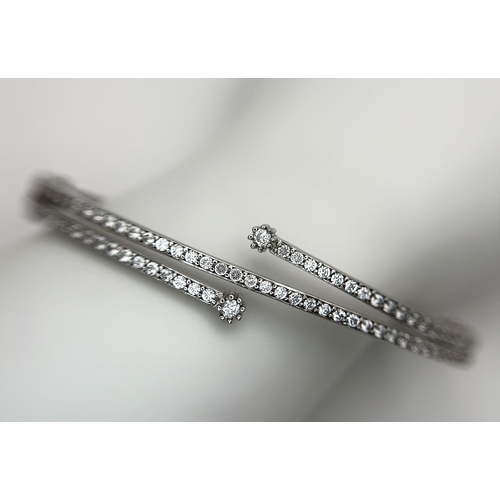 554 - A 14K White Gold and Diamond Crossover Bangle Bracelet. c.100 micro-claw pave set diamonds of c.1ctw... 