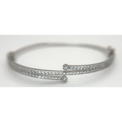 554 - A 14K White Gold and Diamond Crossover Bangle Bracelet. c.100 micro-claw pave set diamonds of c.1ctw... 