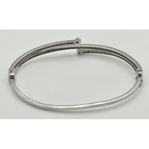 554 - A 14K White Gold and Diamond Crossover Bangle Bracelet. c.100 micro-claw pave set diamonds of c.1ctw... 