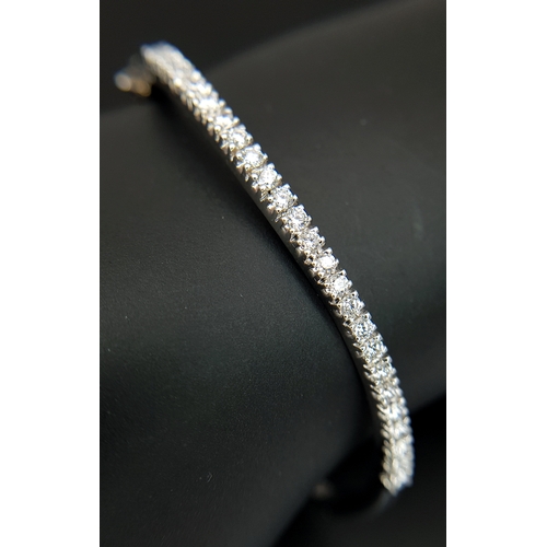 568 - An 18K White Gold (tests as) and Diamond Wave Bangle. 0.87ctw or round brilliant cut diamonds in a m... 