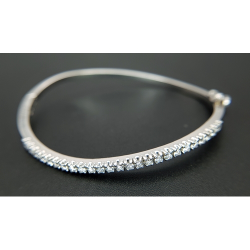 568 - An 18K White Gold (tests as) and Diamond Wave Bangle. 0.87ctw or round brilliant cut diamonds in a m... 