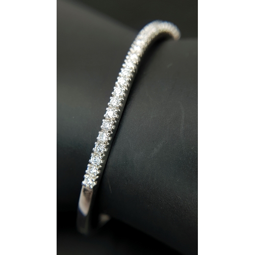 568 - An 18K White Gold (tests as) and Diamond Wave Bangle. 0.87ctw or round brilliant cut diamonds in a m... 