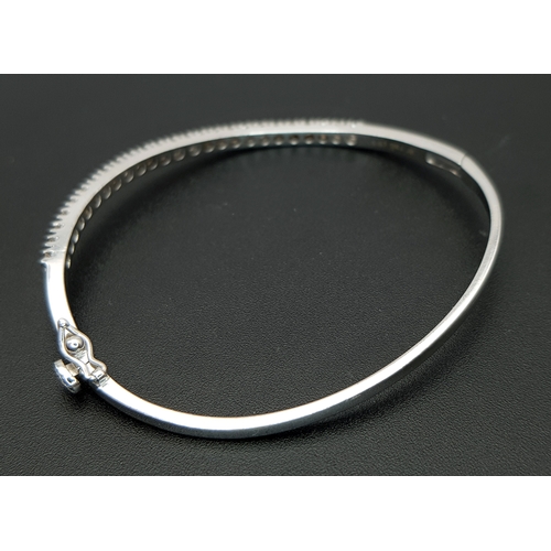 568 - An 18K White Gold (tests as) and Diamond Wave Bangle. 0.87ctw or round brilliant cut diamonds in a m... 