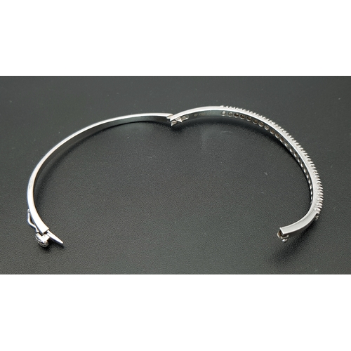 568 - An 18K White Gold (tests as) and Diamond Wave Bangle. 0.87ctw or round brilliant cut diamonds in a m... 