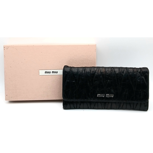 579 - A Miu Miu Nappa Matelassé Flap Wallet. Black matelassé pleated leather exterior with silver-toned lo... 