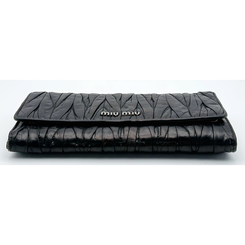 579 - A Miu Miu Nappa Matelassé Flap Wallet. Black matelassé pleated leather exterior with silver-toned lo... 