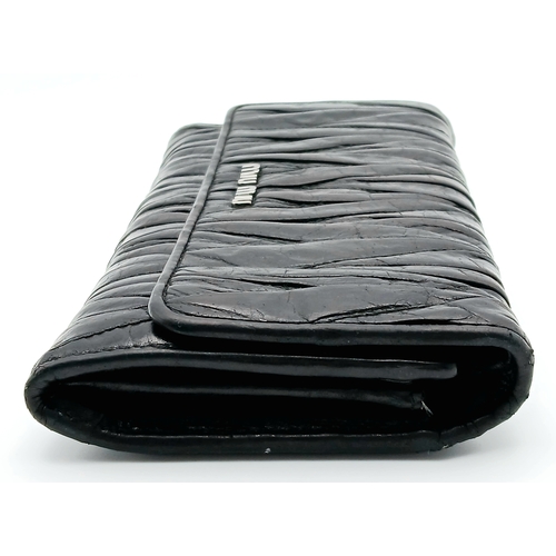 579 - A Miu Miu Nappa Matelassé Flap Wallet. Black matelassé pleated leather exterior with silver-toned lo... 