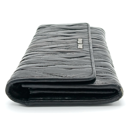 579 - A Miu Miu Nappa Matelassé Flap Wallet. Black matelassé pleated leather exterior with silver-toned lo... 