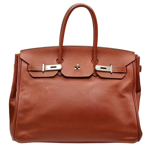 An Herm&egrave;s Brick Red Courchevel Birkin 35 Handbag. Brick red Courchevel leather exterior with silver-toned hardware, double rolled top handles, front leather sangles and four protective base studs. Turn-lock closure opening to an orange leather interior with one zipped inner side pocket and one open inner side pocket. Square E stamp (2001).  Approx 35cm length x 27cm height. A few very light stains to the interior and a minor 1.5cm scratch to the exterior leather. Please see photos or request a condition report. Ref: H009