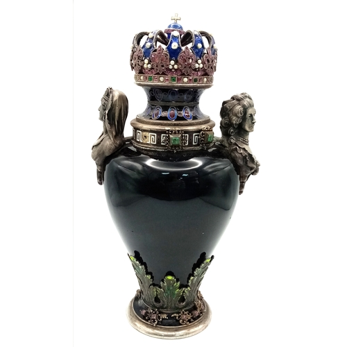 A Rare Viennese 19th Century Silver, Enamel and Stone Set Urn. Baluster form raised on a circular foot with stone set filigree decoration. Shoulders mounted with busts of Cleopatra and Marie Antoinette. Collar decorated with a white enamelled Greek key border and cabochon settings. Lid in the form of a crown set with rubies, emeralds and pearls, ruby set fleur-de-lys, and a finial modelled as a Sovereign Orb with an enamelled cross. One stone missing. Mounted in a purpose made leather display case. 22cm tall. Provenance: The case has an old paper label for Sotheby's, 4/7/89, lot 383. Winning bidder must collect from Cadmore HQ or arrange a courier.