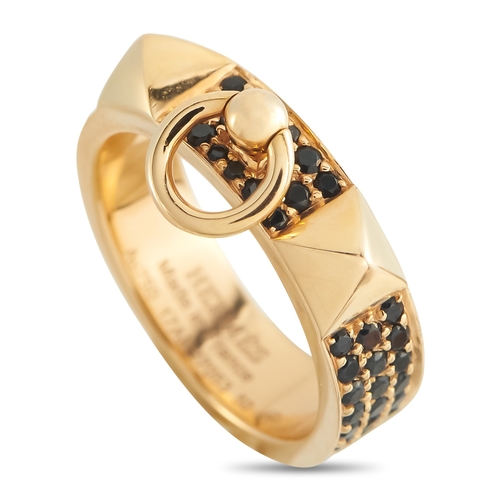 A Hermes Collier de Chien 18K Yellow Gold Spinel Ring. The yellow gold band alternates between pav spinel panels and raised pyramid-like Mdor studs. The black spinel adds depth against the gold, while the sculpted studs and central detail give the ring its signature edge. Good Condition,  comes with a gift box. Ring size: 5 (UK size J½). Total weight: 6.6 grams. *This item is held at Cadmore USA Office in Pennsylvania, USA and will be shipped from there. Buyers will be responsible for direct shipping payments.*