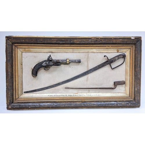 A Battle of Waterloo Relic Board - Containing Trophies Recovered From The Ridge At Mont Saint-Jean, Waterloo, Between The Years of 1828 -1853. Displayed in the Sergeant's Mess of the 73rd Regiment of Foot. The period frame contains three items - A French Cavalry Pistol, A British Officers Cavalry Sword and a British Brown Bess Socket Bayonet. Sergeant Mess 73rd Foot - Hand Written to Top Right Hand Corner Verso. 105x 56cm.