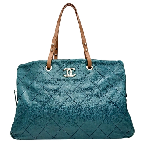 A Chanel Quilted Leather Tote Bag. Dark teal quilted leather exterior with silver-toned hardware, CC logo detail, tan leather shoulder straps and protective base studs. Open-top design opens to a charcoal-blue textile interior with two main compartments, a central zipped compartment, two open inner side pockets, and a zipped inner side pocket. Comes with a certificate of authenticity and an authenticity card. Approx 44cm length x 31cm height. Some light signs of wear to the base corners, but in good overall condition. Please see photos or request a condition report. Ref: 29063.