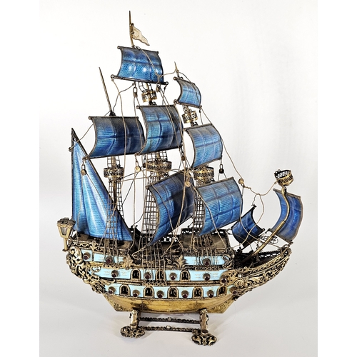 Antique Austrian gilt sterling silver and enamel nef ship. An ornate sterling silver model of a ship on a stand, with jewelled mounts and pearls, lanterns at the rear, turquoise enamel panels armor the hull, and fully rigged blue guilloché sails. Stamped “925” on the ship’s keel. Front mast is unsoldered. Enamel panels and guilloché are in good overall condition, with no missing enamel. 13.5 inches high × 4 inches wide. Weight: 52.6 oz. One sail is loose but not broken; needs slight polishing.