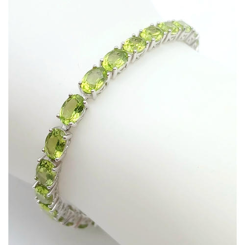 515 - An Elegant Sterling Silver Peridot Set Tennis Bracelet-20cm Length. Set with Thirty-Two 5 x 4mm Oval... 