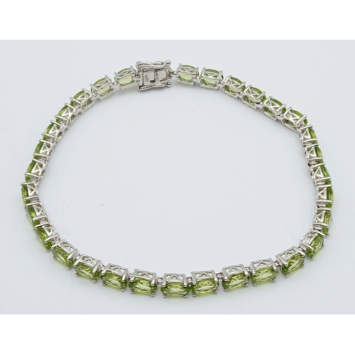 515 - An Elegant Sterling Silver Peridot Set Tennis Bracelet-20cm Length. Set with Thirty-Two 5 x 4mm Oval... 