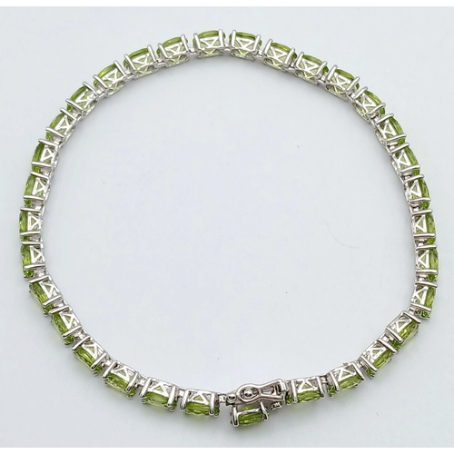 515 - An Elegant Sterling Silver Peridot Set Tennis Bracelet-20cm Length. Set with Thirty-Two 5 x 4mm Oval... 