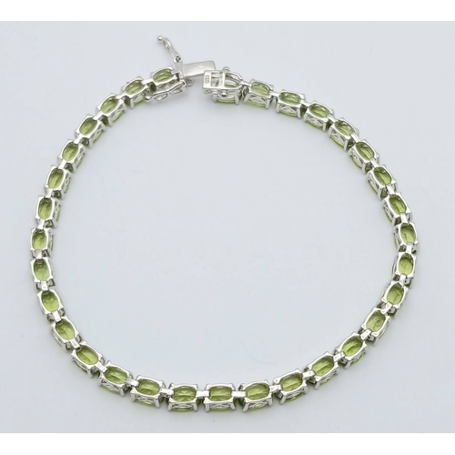 515 - An Elegant Sterling Silver Peridot Set Tennis Bracelet-20cm Length. Set with Thirty-Two 5 x 4mm Oval... 