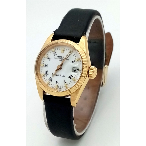 A Rolex 18K Gold Cased Automatic Ladies Datejust Watch. Model 6917. Black leather strap. 18k gold case - 26mm. White dial with Tiffany and Co. marking, Roman numerals and date window. Fluted bezel. In working order. Comes with a WCSA and Watch register report. Ref: 028637.