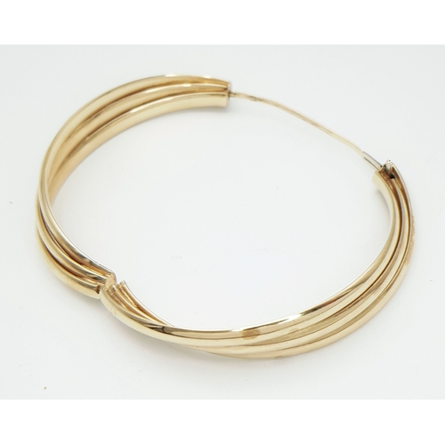 50 - A 9K Yellow Gold Twist Bangle. 14mm widest part. Clip open design. Two small dings. 55mm inner diame... 