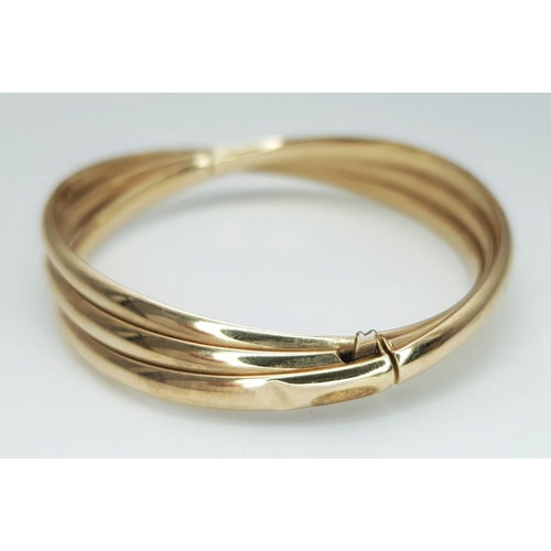 50 - A 9K Yellow Gold Twist Bangle. 14mm widest part. Clip open design. Two small dings. 55mm inner diame... 