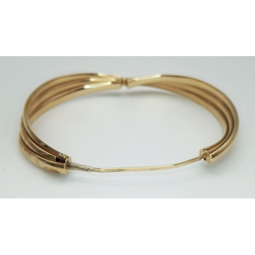 50 - A 9K Yellow Gold Twist Bangle. 14mm widest part. Clip open design. Two small dings. 55mm inner diame... 