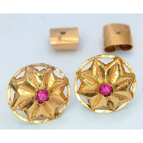 30 - A Pair of 18K Yellow Gold (tests as) and Ruby Floral Form Stud Earrings. 1.6g total weight.
