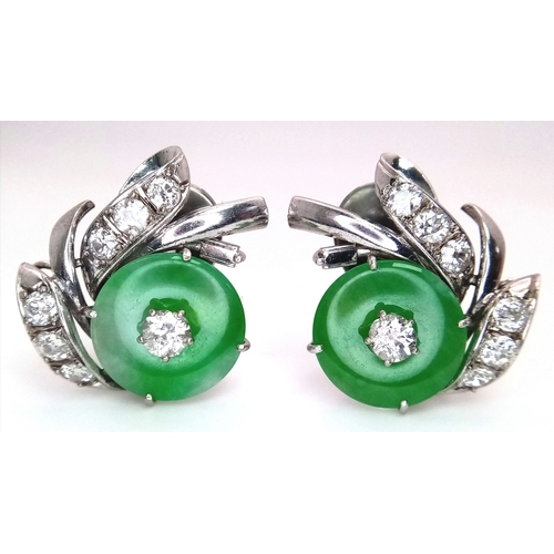 A Stunning Pair of Jade and Diamond Earrings - Each having a circular jade piece with a 0.20ct round brilliant cut centre stone - and a further 0.60ctw of round brilliant cut diamonds in wave form. 1.6ctw of diamonds having G-H colour and VS2 clarity. Metal setting is composed of a gold, silver and palladium alloy. 2.5cm x 2.5cm. 12.5g total weight. MT3.