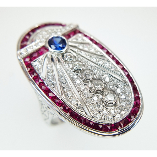 A Head-Turning 18K White Gold Mult-Gemstone Cocktail Ring in Oval Shield Form. A 0.47ct sapphire sits atop five round brilliant cut graduated diamonds. A pave set diamond cluster design with openwork and a square cut ruby border of 1.46ctw completes this masterpiece. 0.70ctw of diamonds with G-H colour and VS2-SI1 clarity. Size P 1/2. 10.94g total weight.