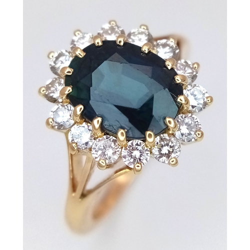 A Classic 18K Yellow Gold, Sapphire and Diamond Ring. A 2ct oval cut teal sapphire with a round brilliant cut diamond surround  - 0.70ctw having F colour and VS2 clarity. Size M 1/2. 5.1g total weight. MT15.