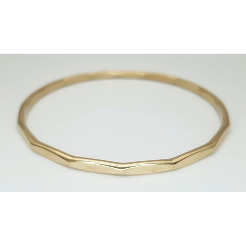 23 - A 9K Yellow Gold Multi-Faceted Gold Bangle. 4mm width. 63mm inner diameter. 15.75g