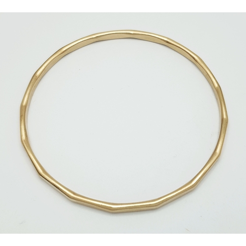 23 - A 9K Yellow Gold Multi-Faceted Gold Bangle. 4mm width. 63mm inner diameter. 15.75g