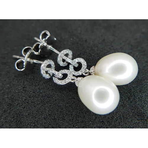 373 - A Pair of 18K White Gold, Pearl and Diamond Drop Earrings. 8mm pear shaped pearls with diamond set c... 