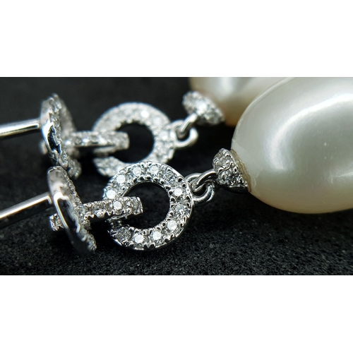 373 - A Pair of 18K White Gold, Pearl and Diamond Drop Earrings. 8mm pear shaped pearls with diamond set c... 