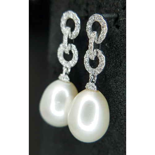 373 - A Pair of 18K White Gold, Pearl and Diamond Drop Earrings. 8mm pear shaped pearls with diamond set c... 
