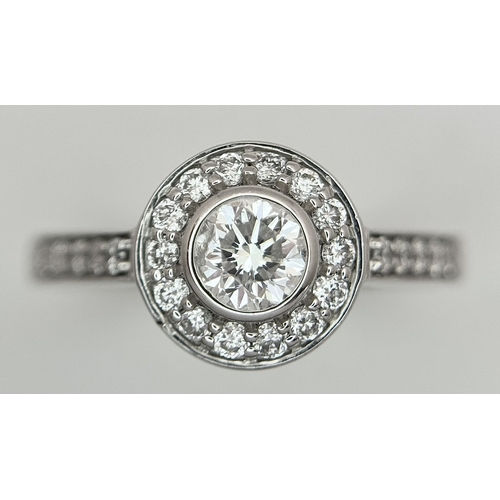 132 - An 18K White Gold, Diamond Solitaire Ring with a Halo and Diamond Set Shoulders. Centre Stone 0.26ct... 