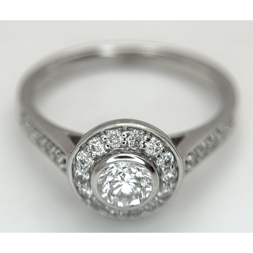 132 - An 18K White Gold, Diamond Solitaire Ring with a Halo and Diamond Set Shoulders. Centre Stone 0.26ct... 