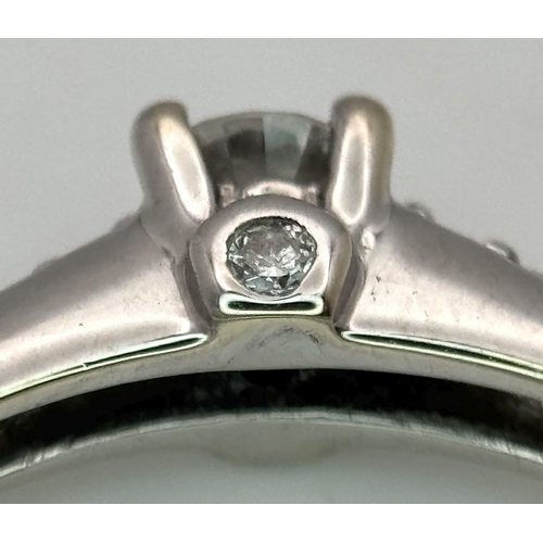 65 - An 18K White Gold, Diamond Dress Ring. 0.15ct round brilliant cut centre stone with diamond accents.... 