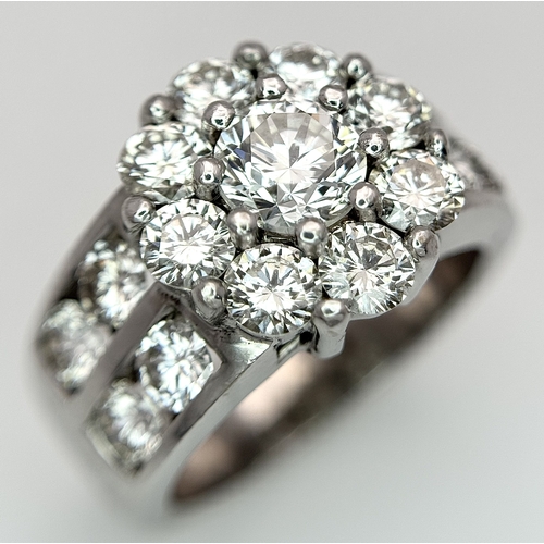 An 18K White Gold and Diamond Dress Ring. A 0.75ct round brilliant cut diamond centre stone with a 2ctw round brilliant cut diamond surround. A further 1ctw of channel set round brilliant cut diamonds complete this statement masterpiece. c.3.75ctw of diamonds having G-H colour with SI1 clarity. Size N 1/2. 13.2g total weight.