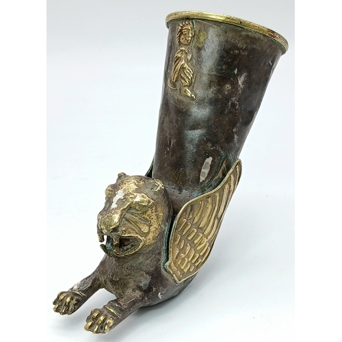 An Antique Persian Islamic Gilt Silver Rhyton Cup. In the form of a winged lion with gilt highlights, the flared cup decorated with a relief figure. Tested as 925 sterling silver. Measures 12cm in height. Total weight 92.4g.
