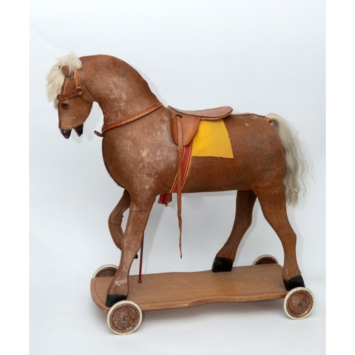 1403 - VINTAGE PULL ALONG HORSE a pony skin pull along horse, fitted with a saddle and mounted on a painted... 