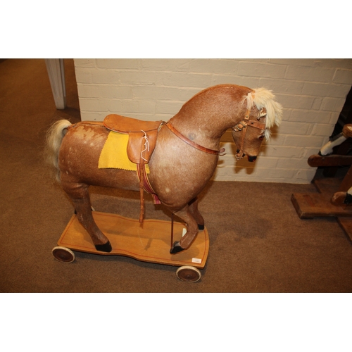 1403 - VINTAGE PULL ALONG HORSE a pony skin pull along horse, fitted with a saddle and mounted on a painted... 