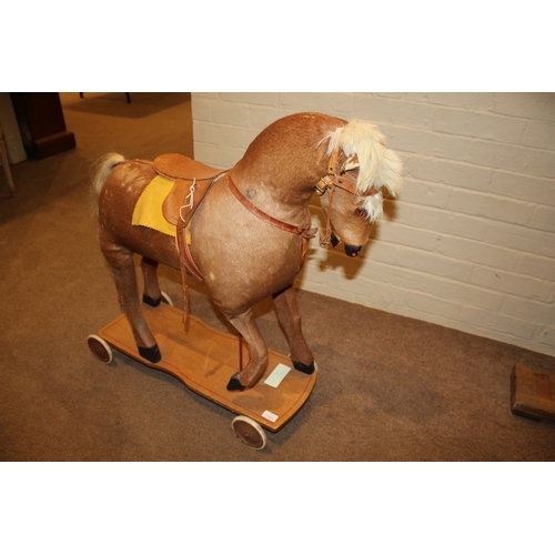 1403 - VINTAGE PULL ALONG HORSE a pony skin pull along horse, fitted with a saddle and mounted on a painted... 