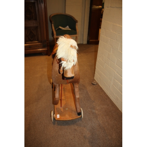 1403 - VINTAGE PULL ALONG HORSE a pony skin pull along horse, fitted with a saddle and mounted on a painted... 