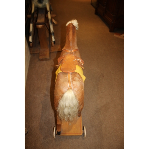 1403 - VINTAGE PULL ALONG HORSE a pony skin pull along horse, fitted with a saddle and mounted on a painted... 