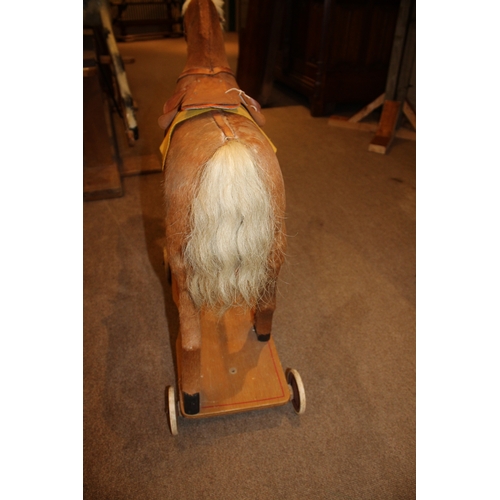 1403 - VINTAGE PULL ALONG HORSE a pony skin pull along horse, fitted with a saddle and mounted on a painted... 