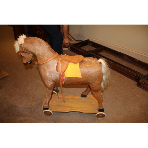 1403 - VINTAGE PULL ALONG HORSE a pony skin pull along horse, fitted with a saddle and mounted on a painted... 