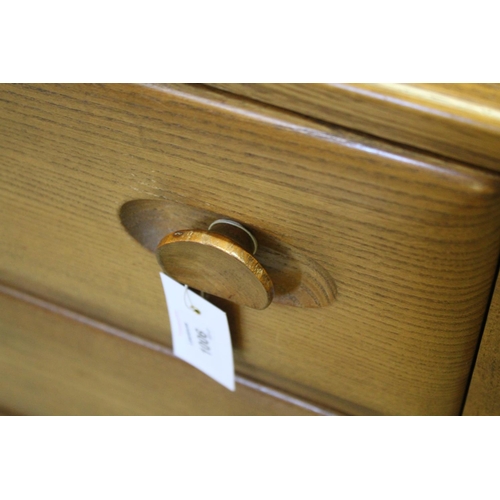 1006 - ERCOL SIDEBOARD a vintage light elm sideboard, with three central drawers flanked by cupboards on ea... 