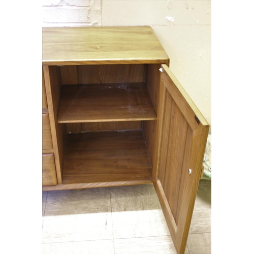 1006 - ERCOL SIDEBOARD a vintage light elm sideboard, with three central drawers flanked by cupboards on ea... 